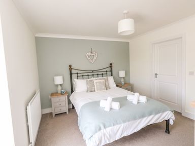 A bedroom with a bed and bedside tables with lamps at Pebbles Reach in Fortuneswell