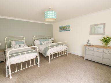 A bedroom with two beds a dresser with a mirror and a painting on the wall at Pebbles Reach in Fortuneswell