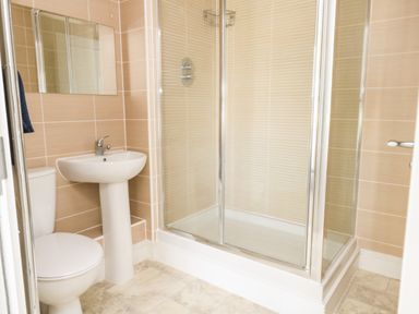 A bathroom with a toilet sink mirror and shower enclosure at Pebbles Reach in Fortuneswell