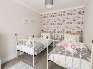 A bedroom with two single beds with star patterned blankets and a cityscape wallpaper at Pebbles Reach in Fortuneswell