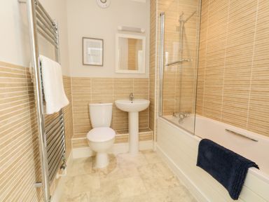 A bathroom with a toilet sink bathtub and towel rail at Pebbles Reach in Fortuneswell