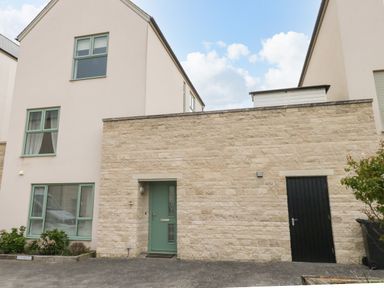 A modern house with stone and cream walls green window frames and doors at Pebbles Reach Fortuneswell