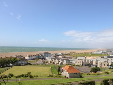 A coastal town view with houses a green field and a beach at Pebbles Reach in Fortuneswell