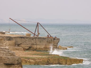 A rocky coastline with an old metal crane overlooking the sea at Pebbles Reach in Fortuneswell