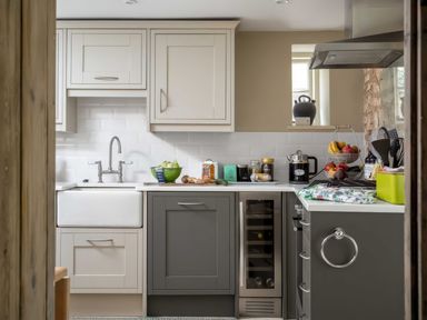 A kitchen with white and grey cabinets a sink a stove and various kitchen items on the counter at East Leaze in Chipping Campden