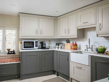 A kitchen with grey and white cabinets a microwave coffee machine and a sink at East Leaze in Chipping Campden