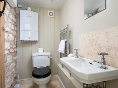 A bathroom with a toilet a sink a towel rail and a boiler on the wall at East Leaze in Chipping Campden
