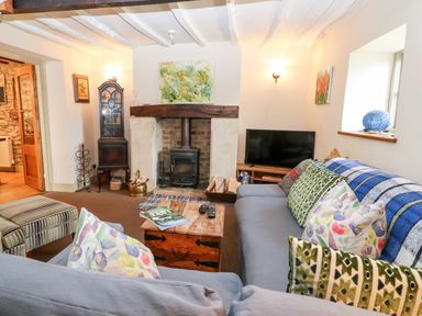 A living room with a fireplace television and a sofa with cushions at Carters Cottage in Stow on the Wold