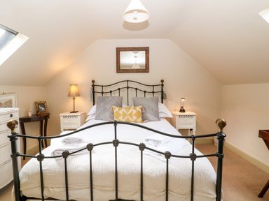 A bedroom with a metal bed frame two bedside tables with lamps and a mirror on the wall at Carters Cottage in Stow-on-the-Wold