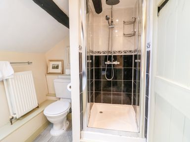 A bathroom with a toilet and a shower with black and white tiles at Carters Cottage in Stow on the Wold