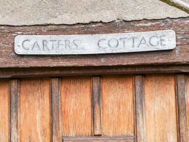 A wooden door with a weathered sign reading Carters Cottage at Carters Cottage in Stow-on-the-Wold