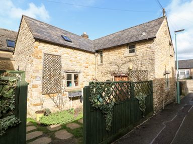 A stone cottage with green wooden fence and climbing plants at Carters Cottage in Stow-on-the-Wold