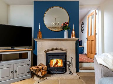A living room with a fireplace a television and a wooden door at Eastnor in Moreton-in-Marsh
