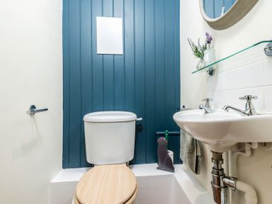A bathroom with a toilet and a sink with a round mirror and shelf at Eastnor in Moreton-in-Marsh