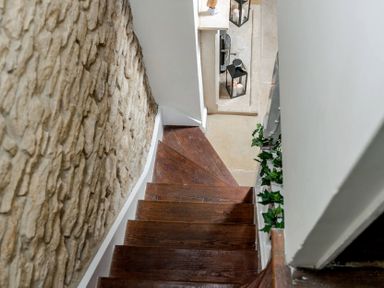 Dark wooden staircase beside a stone wall with candles in glass lanterns at Eastnor in Moreton-in-Marsh