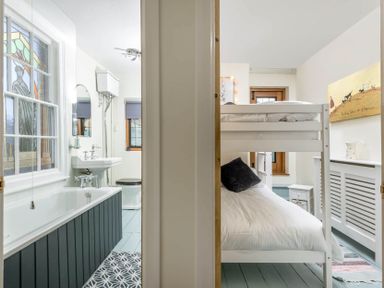 A bathroom with a bathtub sink and toilet next to a bedroom with a bunk bed and a painting at Eastnor in Moreton-in-Marsh