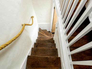 A narrow wooden staircase with white walls and a rope handrail at Eastnor in Moreton-in-Marsh