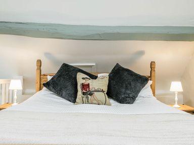 A bed with wood frame two black pillows and a decorative pillow with a woman illustration and bedside tables with lamps at Eastnor in Moreton-in-Marsh
