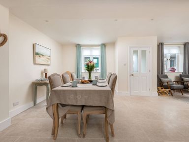 A dining area with a table set for six and a seating area with two chairs at Wall Cottage in Burford