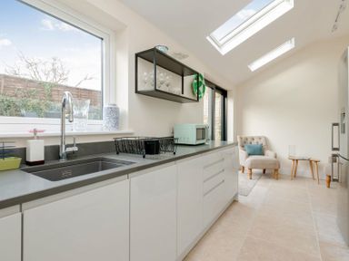 A kitchen with a sink microwave glassware and a chair with a side table at Wall Cottage in Burford
