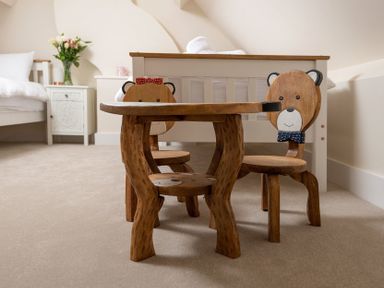 A children's table with two bear-shaped wooden chairs in a bedroom at Wall Cottage in Burford