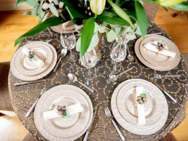 A dining table set for four with plates cutlery glasses and napkins with grape decor at Little Gables in Broadway