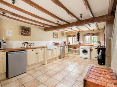 A kitchen with wooden beams on the ceiling and cabinets with appliances at Little Gables in Broadway