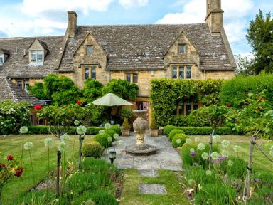 A stone house with a garden path and fountain in front at Little Gables in Broadway