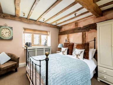 A bedroom with a double iron bed and wooden beams on the ceiling at Little Gables in Broadway