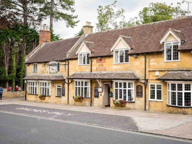 The exterior of the horse and hound pub with a stone facade and flower boxes by the windows at Little Gables in Broadway