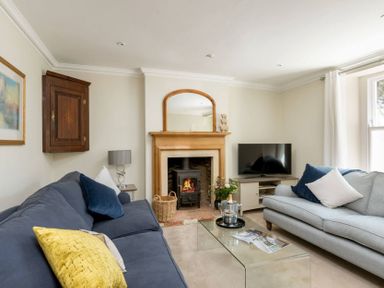 A living room with two sofas a glass coffee table a fireplace and a television at Copperbeech in Stow-on-the-Wold