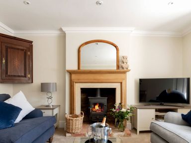 A living room with a fireplace a mirror a television and sofas at Copperbeech in Stow-on-the-Wold