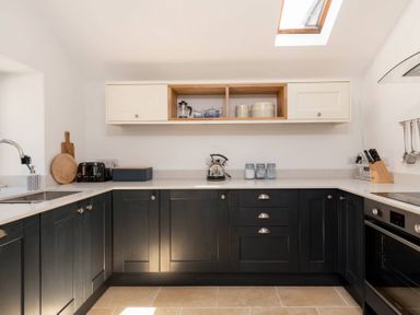 A kitchen with black lower cabinets white upper cabinets toaster kettle and knife block at Copperbeech in Stow on the Wold