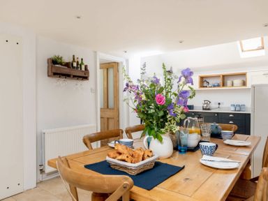 A dining table with croissants flowers and kitchenware in a kitchen at Copperbeech in Stow-on-the-Wold