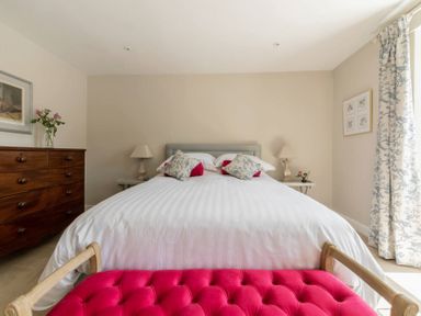A bedroom with a white bed and pink bench at Copperbeech in Stow-on-the-Wold