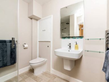 A bathroom with a wall-mounted sink mirror toilet and towel racks at Copperbeech in Stow-on-the-Wold