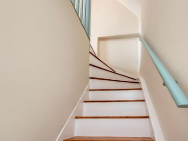 A staircase with wooden steps and a light blue handrail at Copperbeech in Stow-on-the-Wold