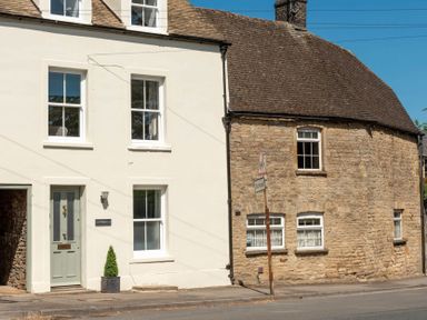 The exterior of a two-tone house with stone and cream-colored walls and multiple windows at Copperbeech in Stow-on-the-Wold