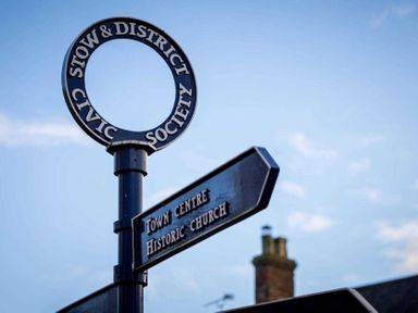 A black street sign post showing directions to town centre and historic church at Copperbeech in Stow-on-the-Wold