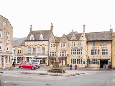A town square with old stone buildings shops and cars at Copperbeech in Stow-on-the-Wold