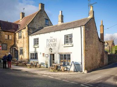 A street corner with a building named The Porch House and outdoor tables and benches at Copperbeech in Stow-on-the-Wold