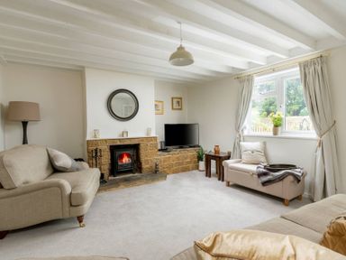 A living room with beige sofas a fireplace and a TV near a window at Holly Cottage Middle Tysoe in Tysoe