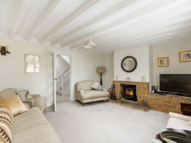 A living room with sofas a fireplace a television and a door showing a staircase at Holly Cottage Middle Tysoe in Tysoe