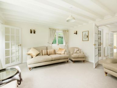 A living room with beige sofas cushions a window with curtains and open French doors at Holly Cottage Middle Tysoe in Tysoe