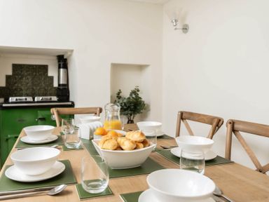 A dining room table set with bowls glasses and a bowl of bread rolls at Holly Cottage Middle Tysoe in Tysoe