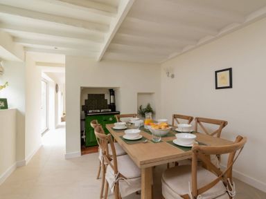 A dining area with a wooden table set with bowls and glasses and wooden chairs in Holly Cottage Middle Tysoe Tysoe