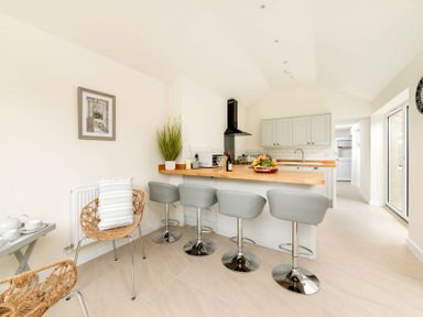 A kitchen with a wooden counter and four grey bar stools at Holly Cottage Middle Tysoe in Tysoe