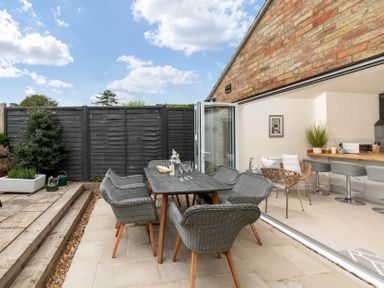 An outdoor patio with a dining table and chairs next to a kitchen with bar stools at Holly Cottage Middle Tysoe in Tysoe