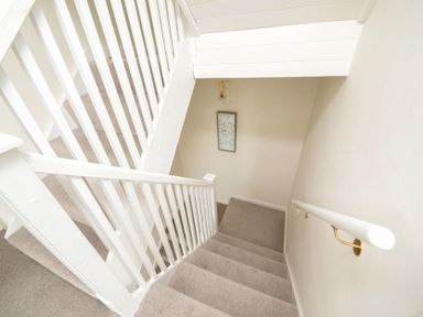 A carpeted staircase with white wooden railings and a framed picture on the wall at Holly Cottage Middle Tysoe in Tysoe