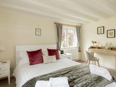 A bedroom with a bed with pillows and blankets bedside tables a dressing table and a chair at Holly Cottage Middle Tysoe in Tysoe